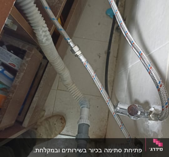 צינורות מים וגומי מתחת לכיור במטבח